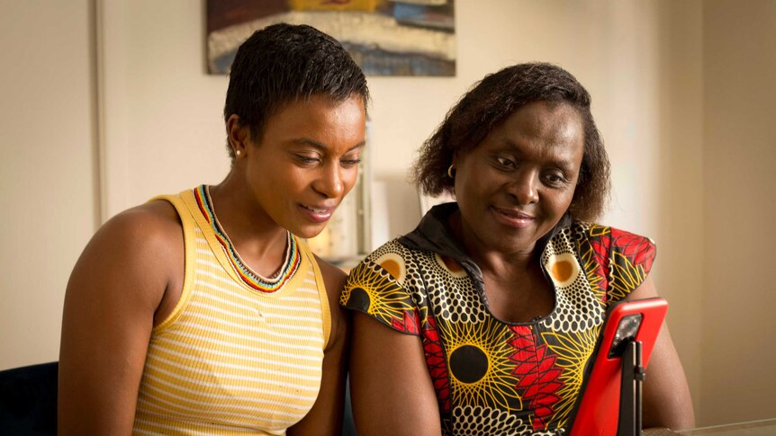 Two women look at an iPhone.