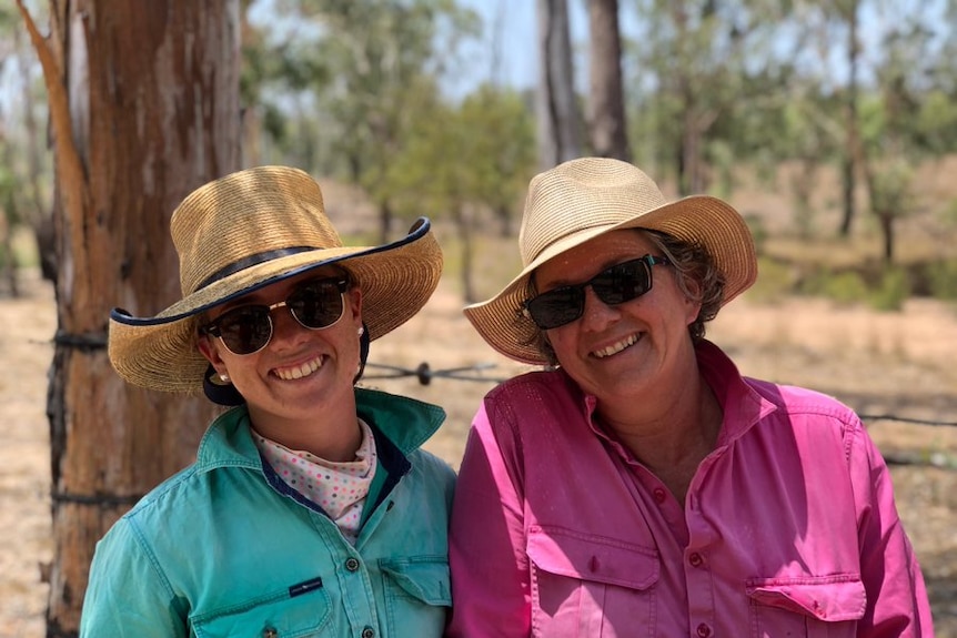 two women in bright shirts and big hats smile in the Australian outback