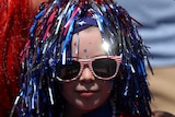 A young girl is wearing a red, white and blue wig with red glasses.