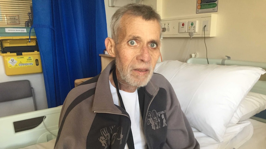 Palliative care patient John Chandler sits on a bed