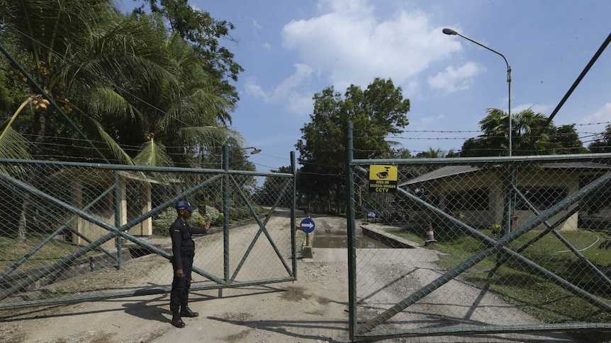 A man in a uniform opens a gate.