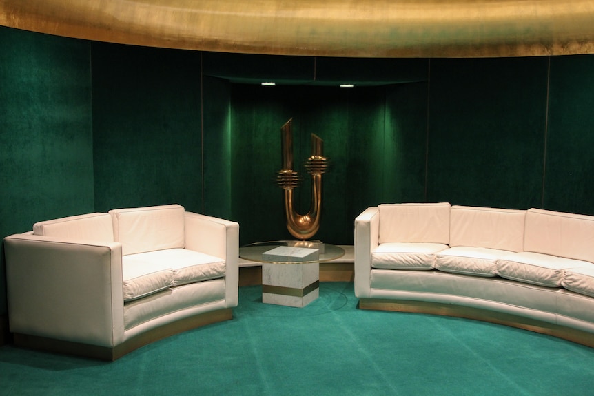 A photo of a room with white sofas and green velvet on the walls with a gold ceiling