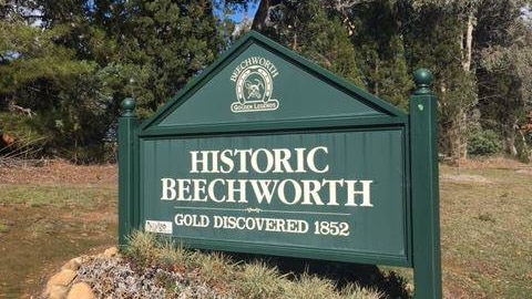 A green wooden sign that says Historic Beechworth planted on the side of road