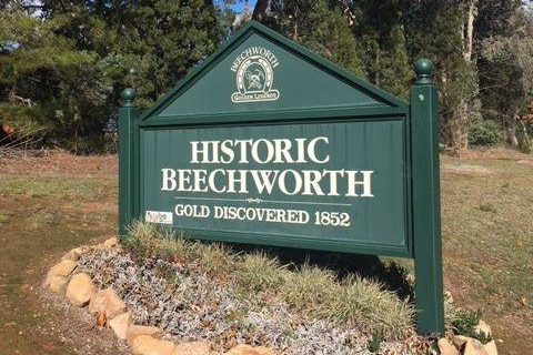 A green wooden sign that says Historic Beechworth planted on the side of road