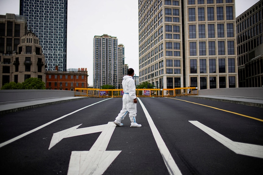 A person in protective suit walking on empty road.