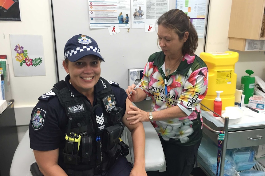 Female police officer gets vaccinated by female nurse.