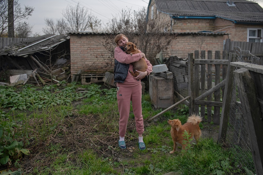 Iryna Stetcenko pets a dog in her yard.