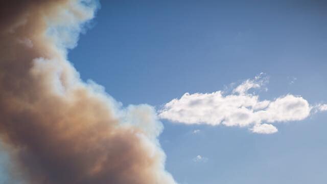 A plume of smoke rises into the sky from a burning bushfire.