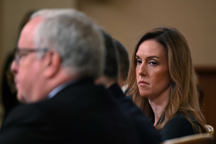 An expressionless woman sits in the House Intelligence Committee hearing.