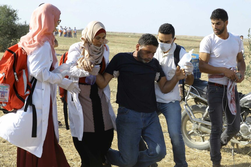 Two female and one male Palestinian medics are seen assisting a wounded man.