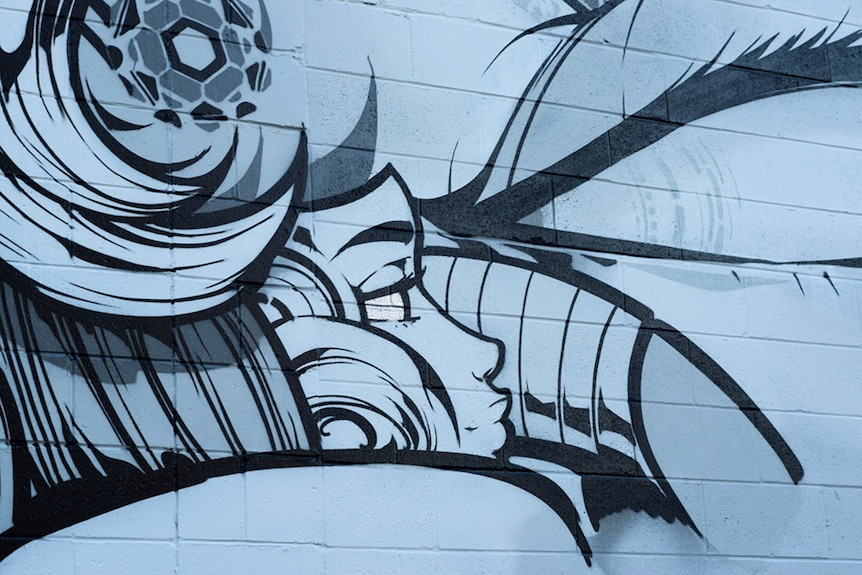 A close up of a mural depicting a woman's face and other symbols in black, white and silver.