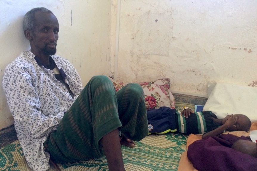 Jama Abdullahi sits with his sick child at a hospital in Somaliland waiting for treatment.