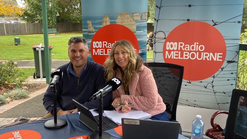 Warwick Long and Richelle Hunt at an outside broadcast in Bacchus Marsh, sitting at a desk with ABC signage around them