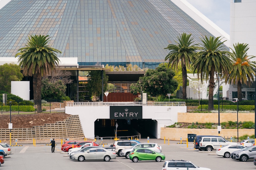 A mid-shot showing the entry to Crown Casino Perth from the carpark with palm trees either side.