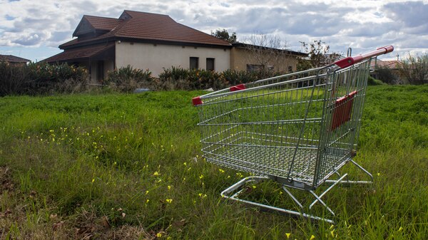 A shopping trolley on a vacant block with house behind