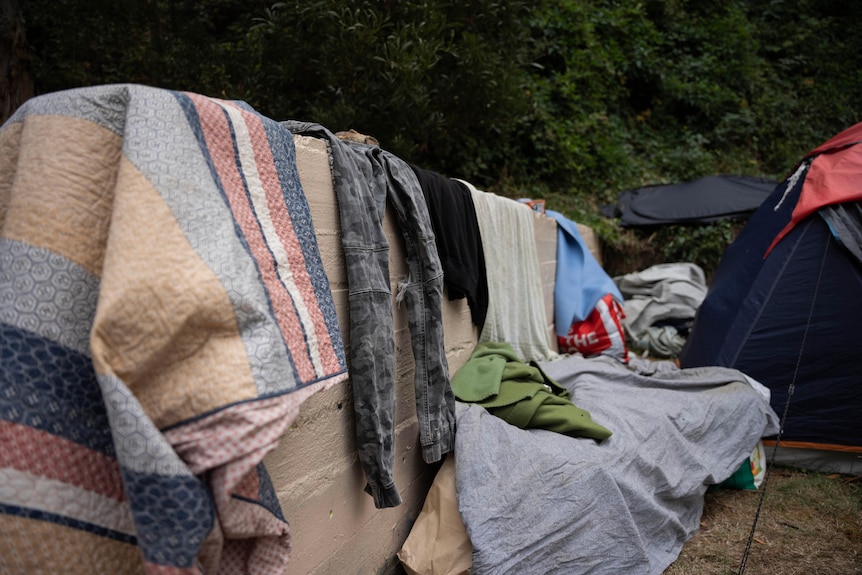 Washing hangs to dry over rocks next to a tent.