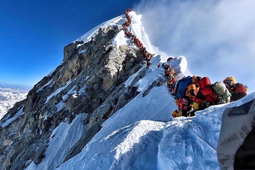 A line of people walk up Everest. 
