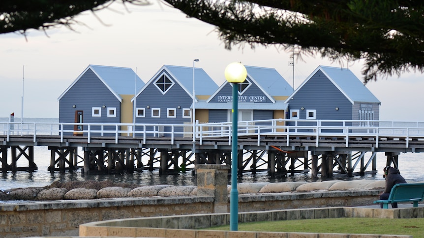 Grey and white shacks built on a pier over the water in Busselton.