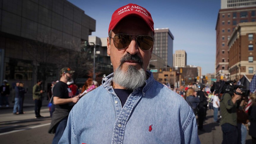 A bearded man in a Make America Great Again cap and sunglasses