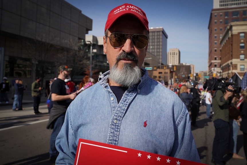 A bearded man in a Make America Great Again cap and sunglasses