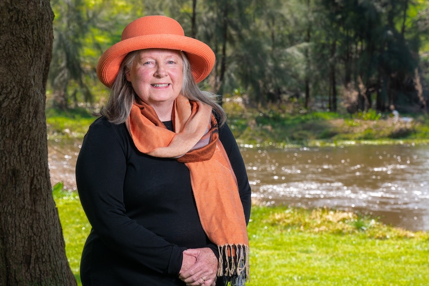 Robyn Hardina wearing hat and scarf and standing in front of river.