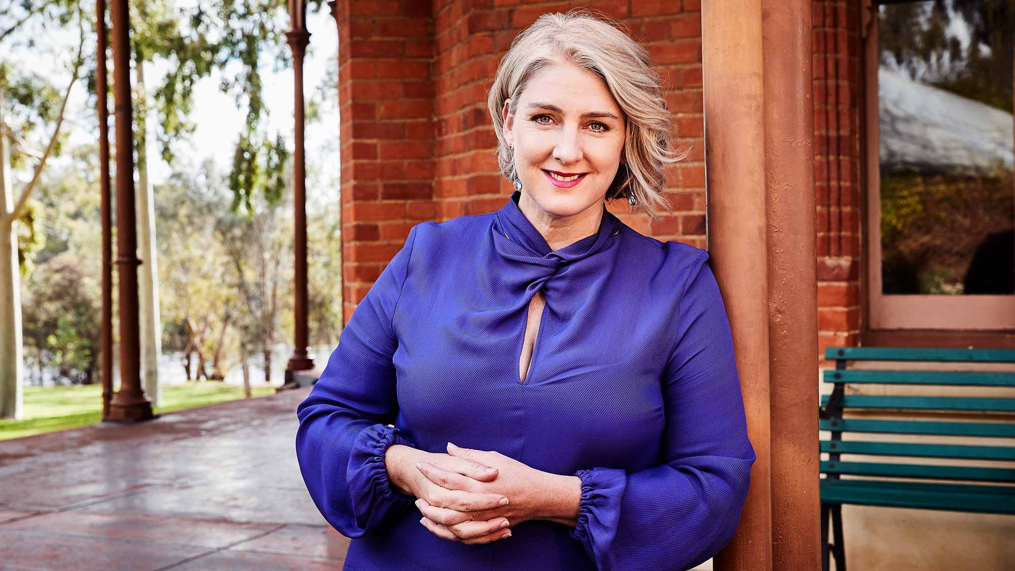 Sinead Mangan, leaning on a verandah post and smiling.