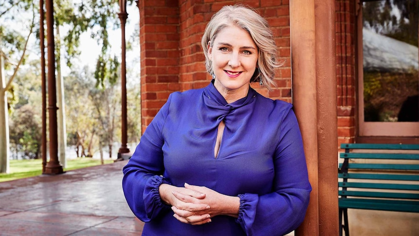 Sinead Mangan, leaning on a verandah post and smiling.