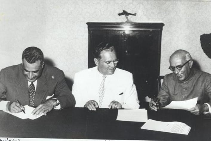 three men smile while working at a meeting table