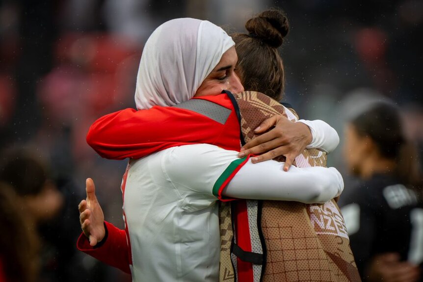 A Moroccan player wearing a hijab receives a big hug from a teammate after a game.