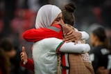 A Moroccan player wearing a hijab receives a big hug from a teammate after a game.
