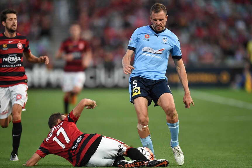 Matt Jurman of Sydney FC is tackled by Alberto Aguilar