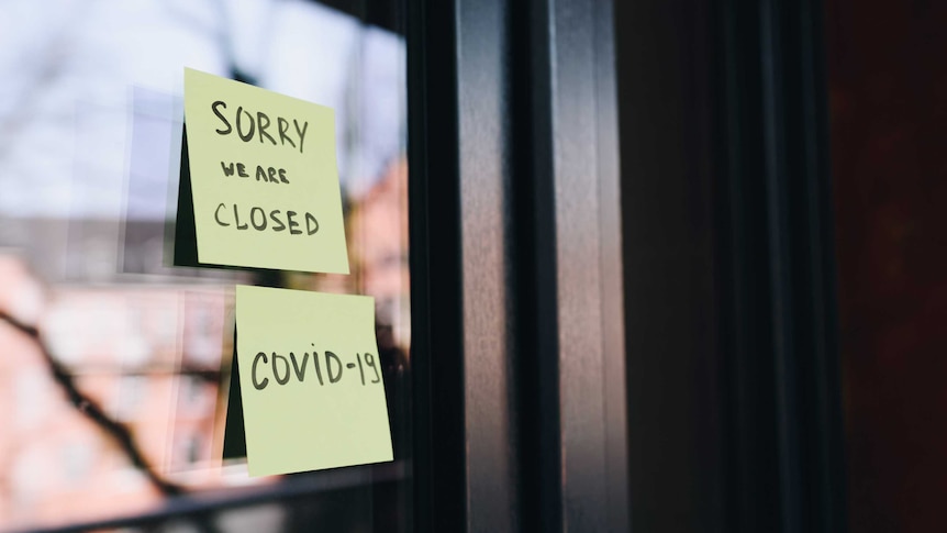 A window with two post-it notes saying "sorry we are closed" and "COVID-19".