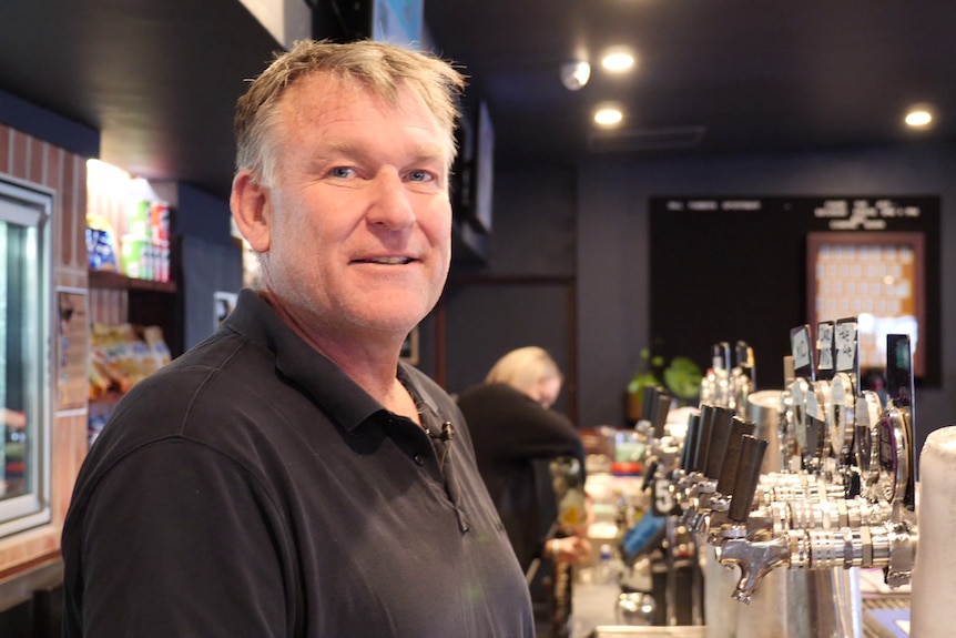 A man stands behind a bar.