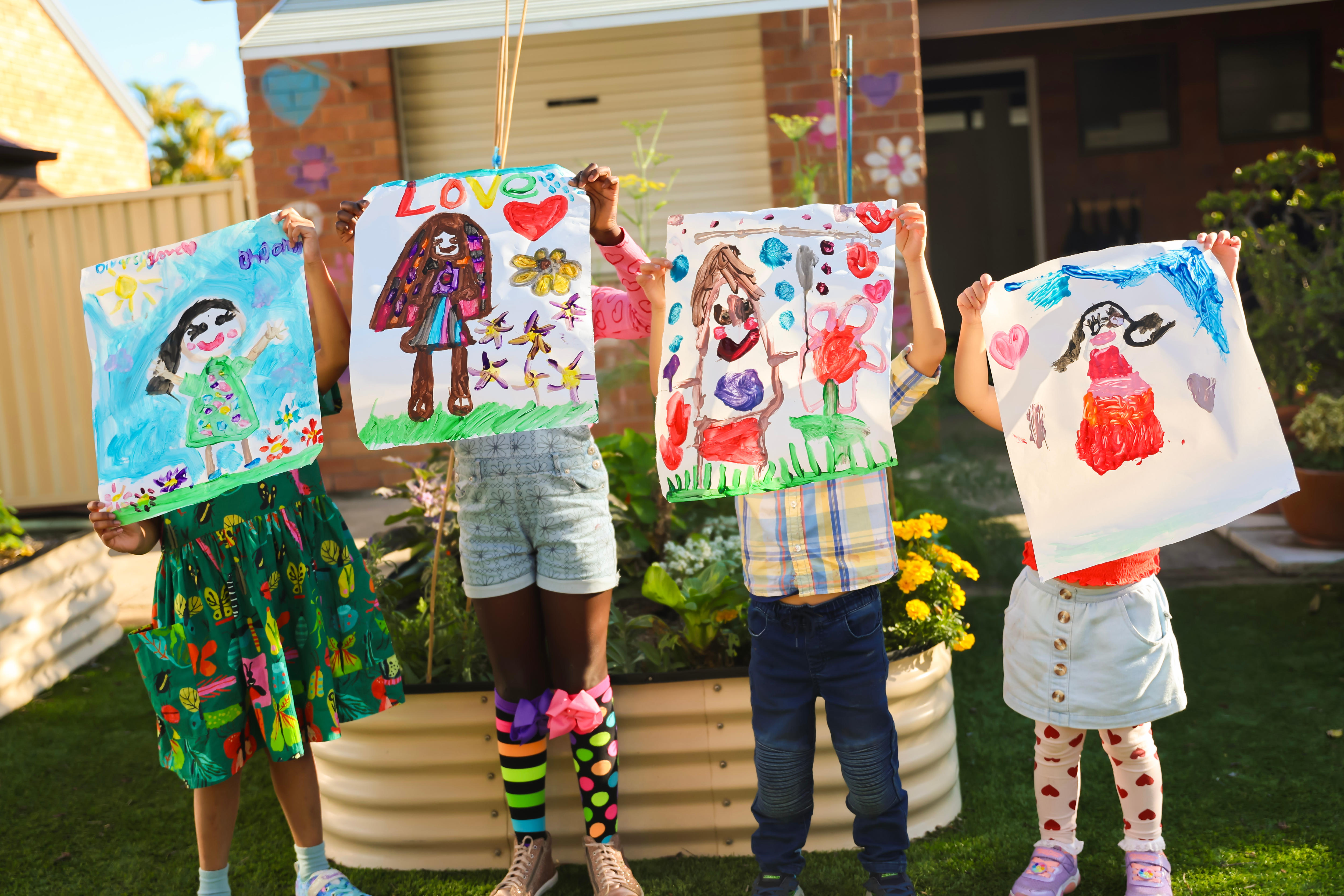 children holding up paintings of their diverse self-portraits. 
