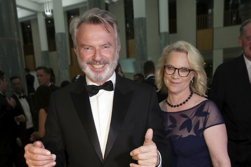 Neill wearing black tie and Tingle in evening gown smiling for camera.