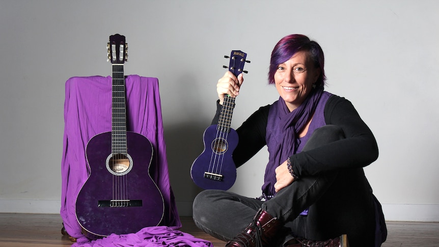 Wollongong circus facilitator Honora Jenkins sits with a guitar and ukulele.