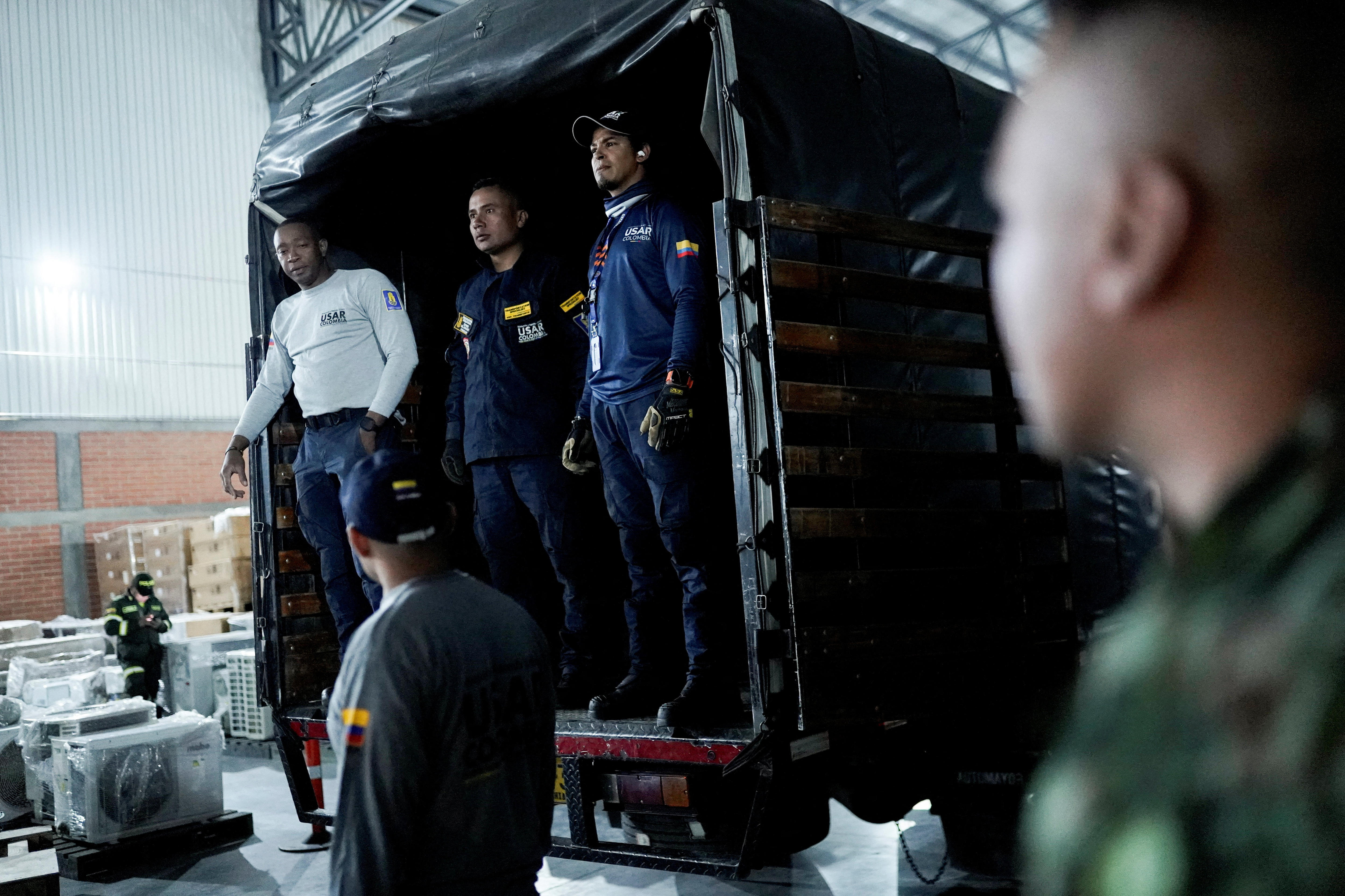 men in search and rescue uniforms stand in the back of a truck 
