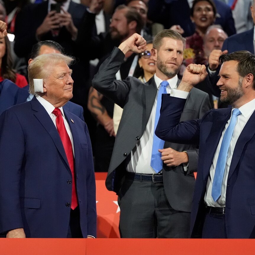 Men hold fists up in celebration as Trump smiles at them