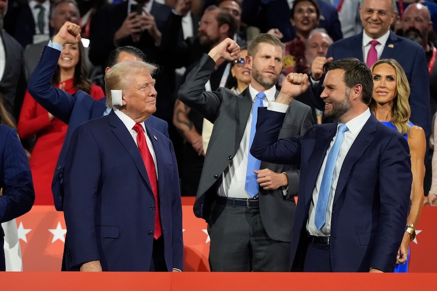 Men hold fists up in celebration as Trump smiles at them