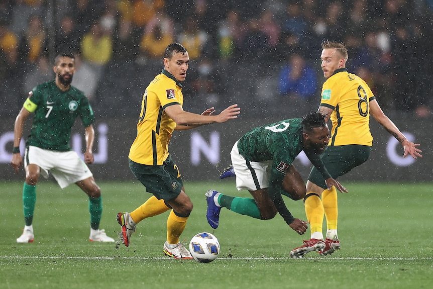 Feras Albrikan falls to the floor with his eyes closed as Trent Sainsbury and James Jeggo stand either side and look behind them