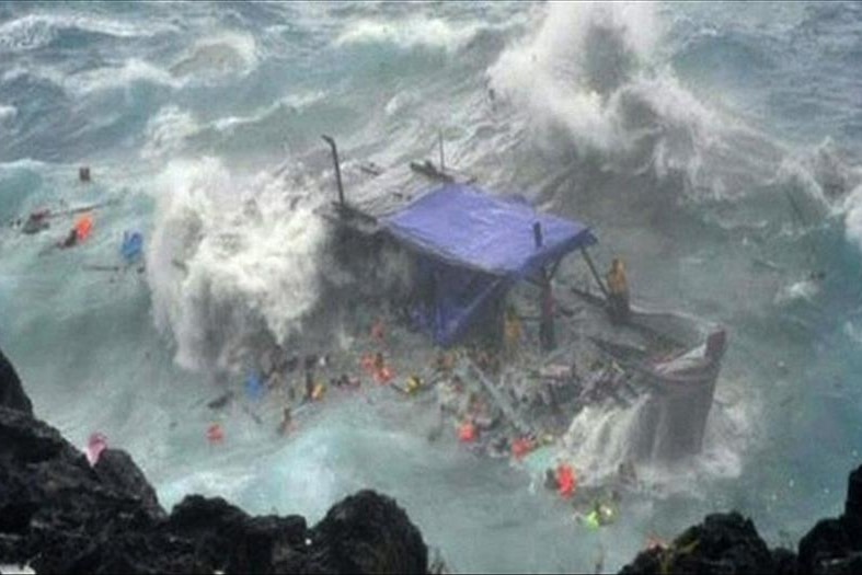 A timber asylum seeker boat smashes against the rocks.