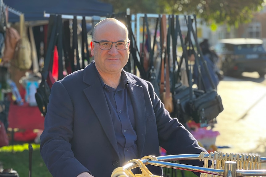 David Szigeti is pictured in front of a clothes rack at the Altona Beach Markets on a sunny day.
