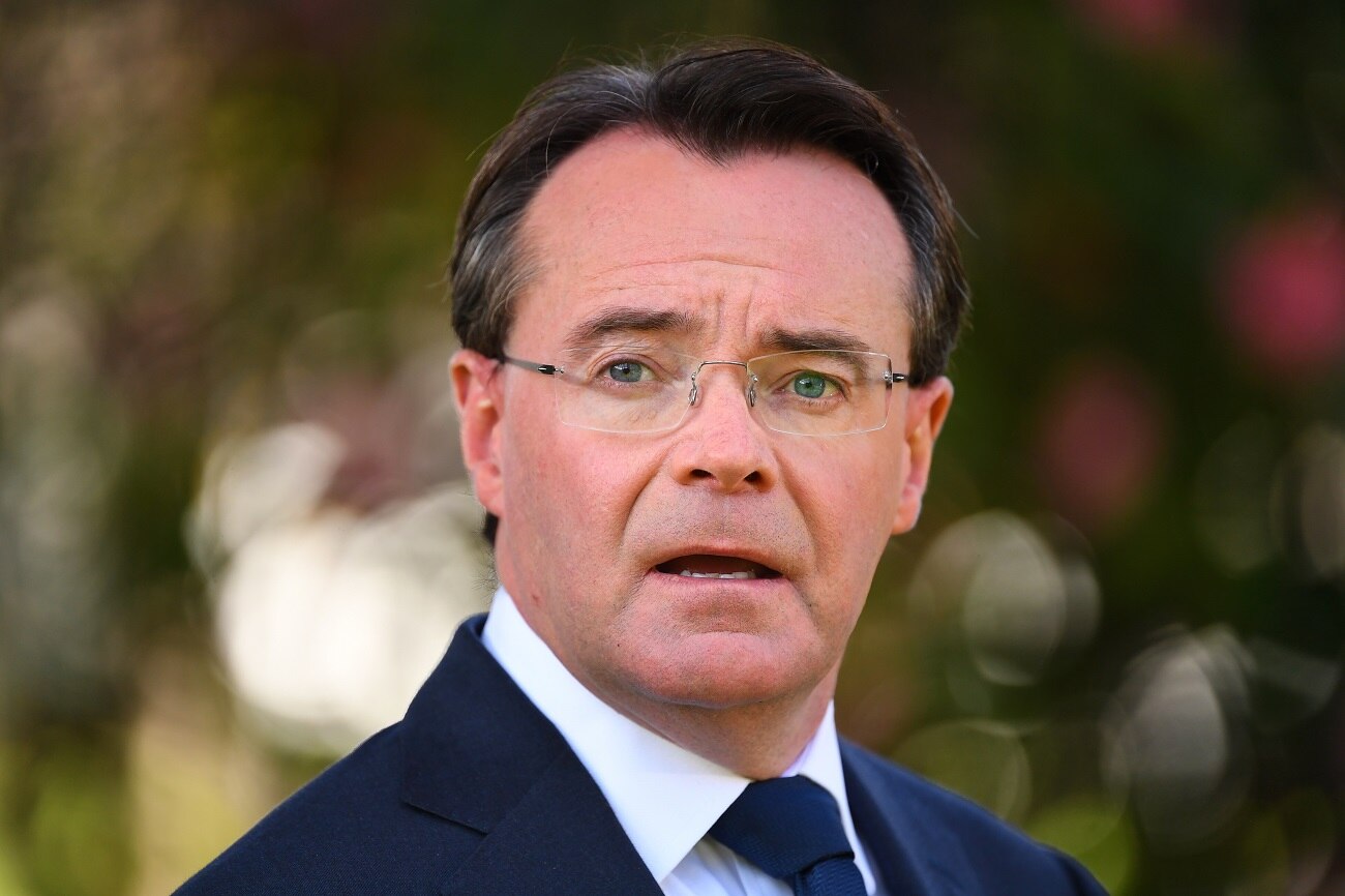 Michael O'Brien, dressed in a suit and blue tie, stands in a park.