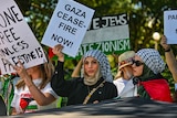Women hold signs reading "Gaza cease fire now!" and "no one is free unless Palestine is" at Hyde Park