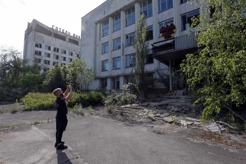 Visitor takes a photo of a building in the abandoned city of Pripyat