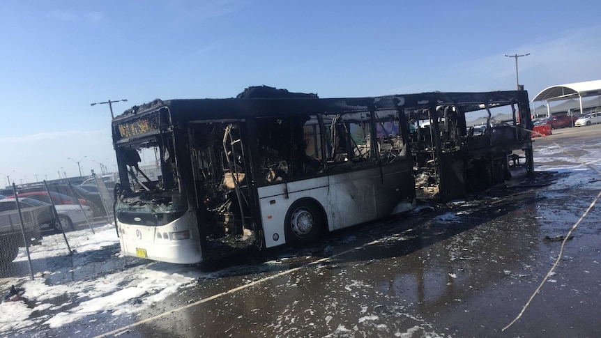 The burnt remains of a bus, blackened and charred.