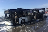 The burnt remains of a bus, blackened and charred.