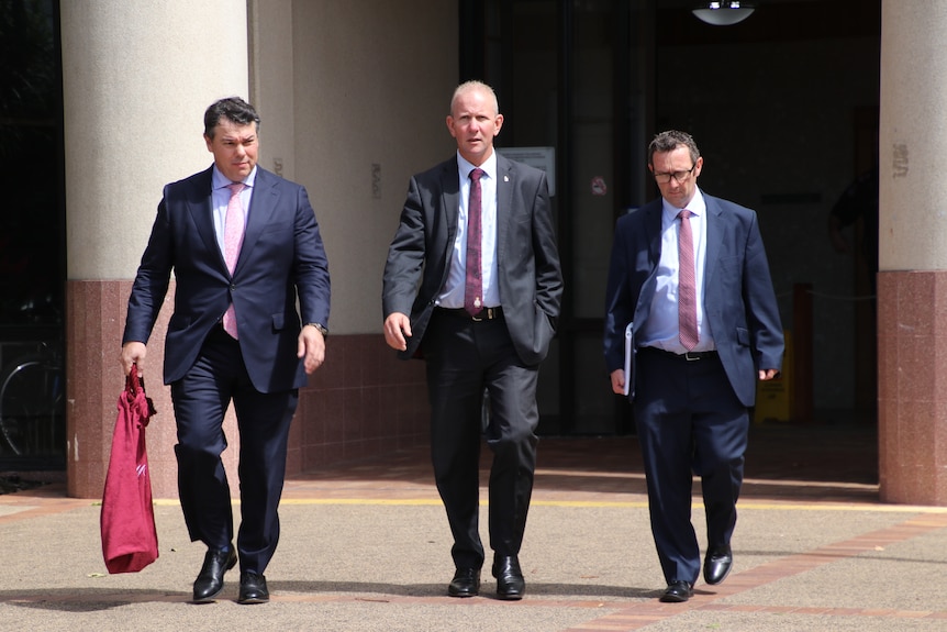 Three men in suits aoutside court.