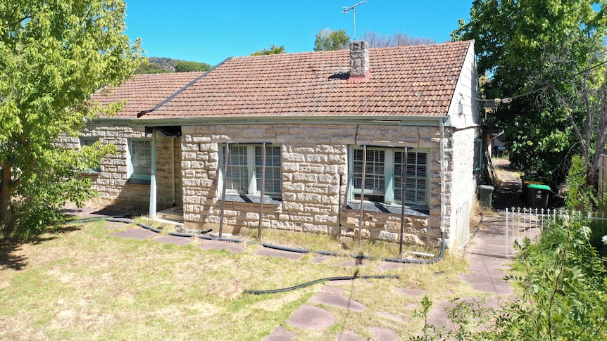 A stone house with metal supports holding up its front wall