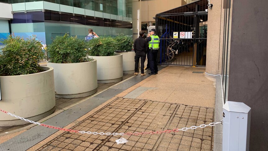 Police stand on a pavement amidst buildings in Adelaide's CBD.